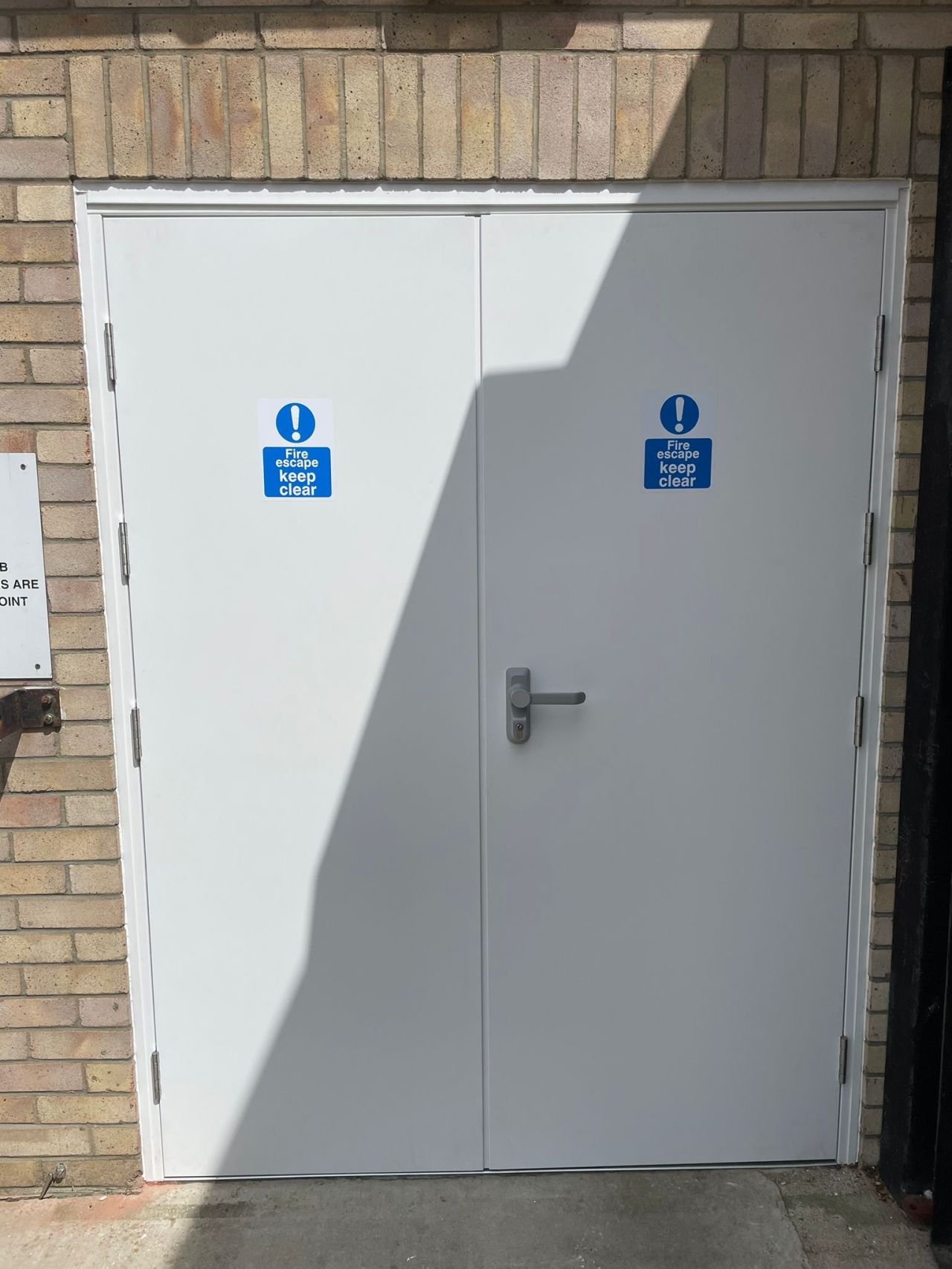 White fire rated door with blue signs on a brick wall