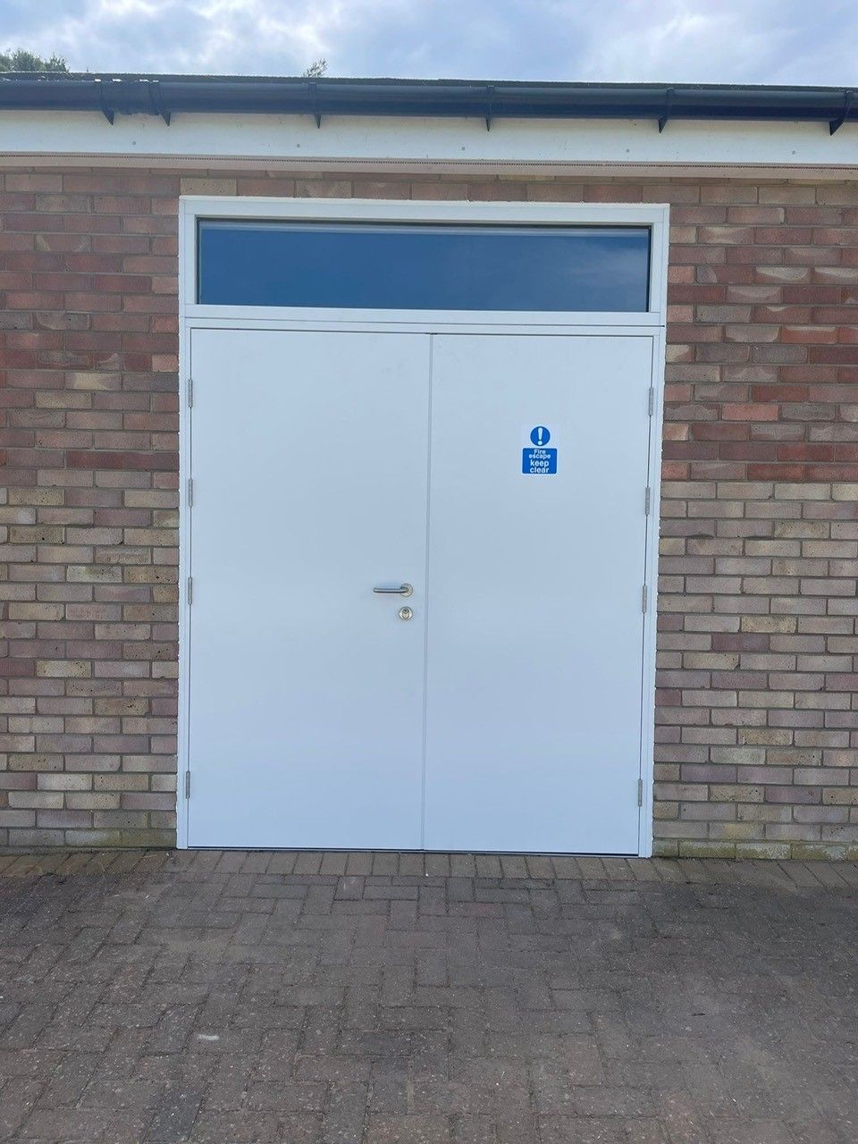 White fire rated door with a blue sign on a brick wall