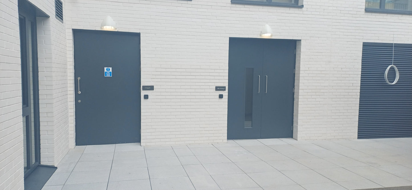 Two blue fire rated doors on a white building facade 